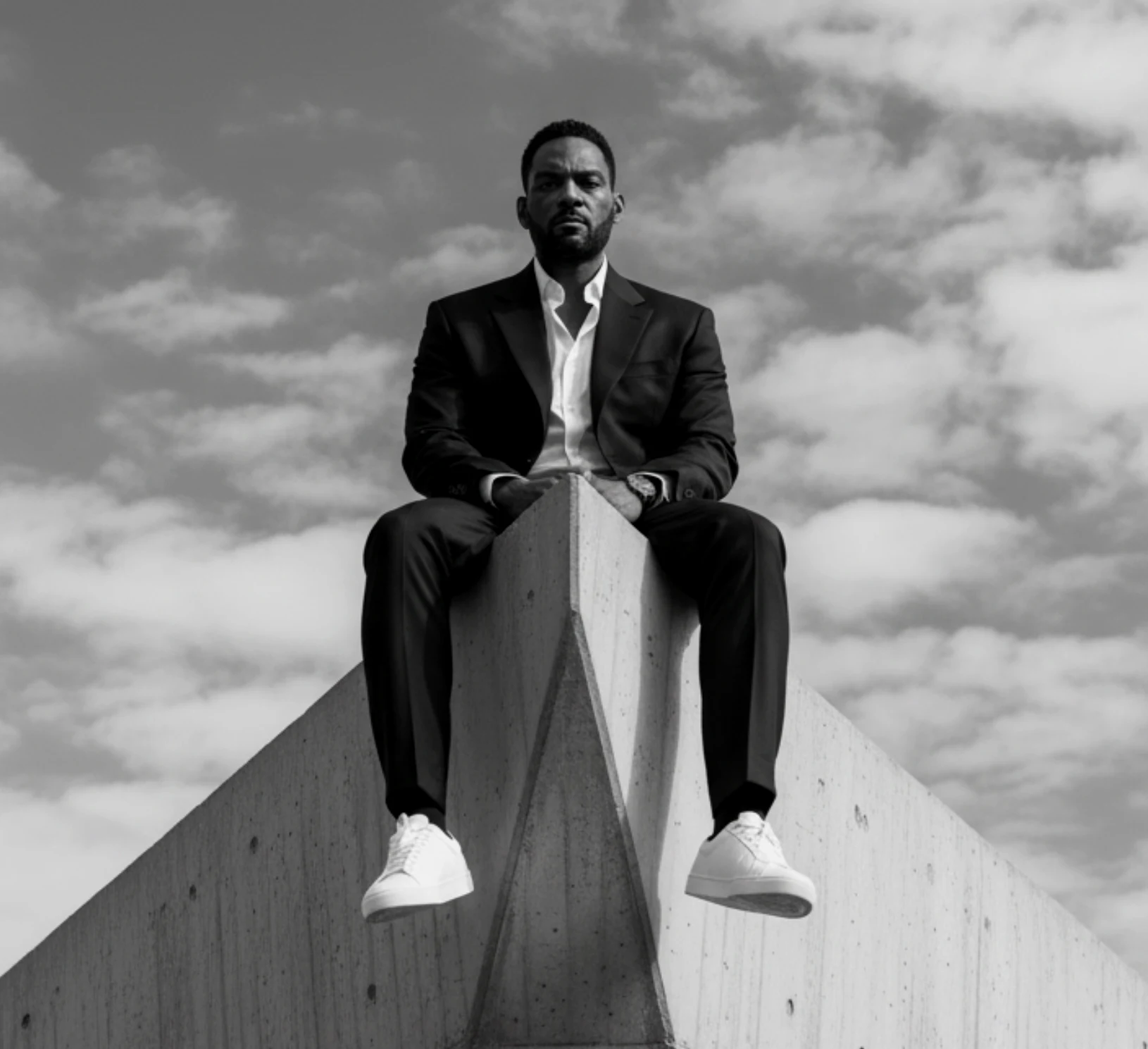 Marcus Martin seated atop a concrete monument against open sky, black and white